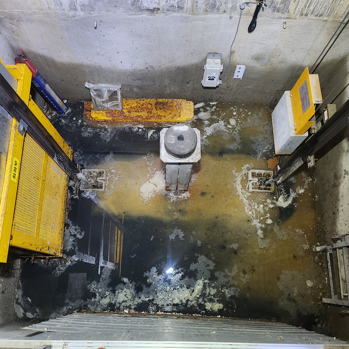 시공 전 물이 고이고 누수 흔적과 오염이 남은 승강기 피트